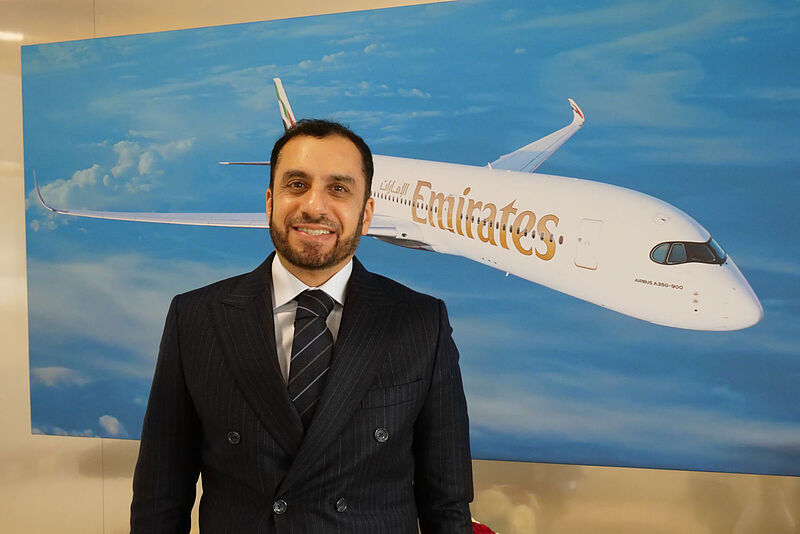 Emirates-Manager Adnan Kazim posiert vor einem Bild eines Flugzeugs der Airline