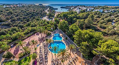 Luftaufnahme des Grupotel Club Cala Marsal auf Mallorca mit Poollandschaft, Sonnenterrasse, Palmen und Blick auf die Bucht von Cala Marsal, umgeben von mediterraner Vegetation und nahegelegenen Ferienanlagen.