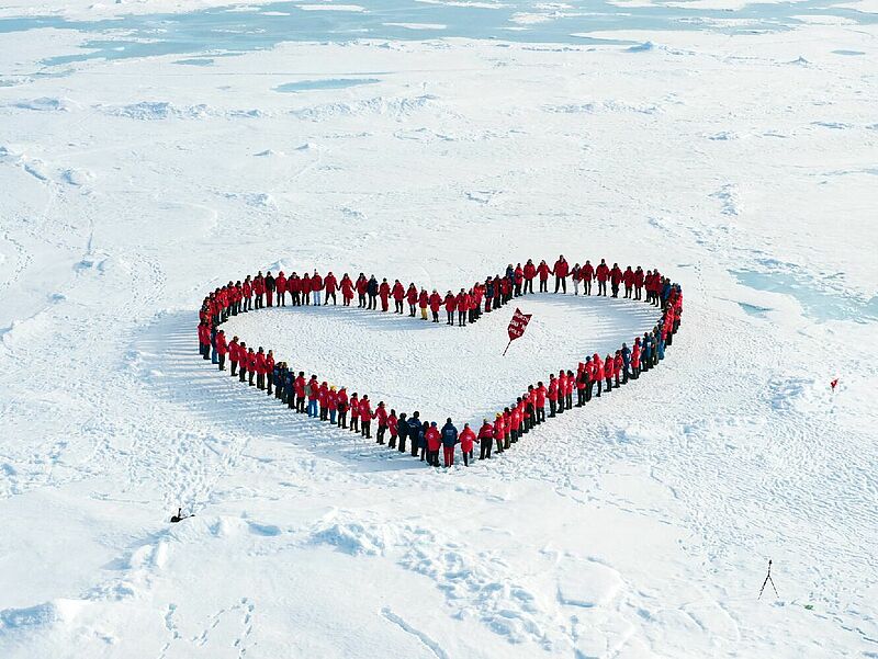 Archivbild mit aktueller Botschaft: Bei der Nordpol-Zeremonie von Poseidon Expeditions reichen sich Passagiere aus aller Welt friedlich die Hand und zeigen Einigkeit. Foto: Anthony Smith