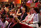 Viele Menschen sitzen in einem großen Saal und reden miteinander