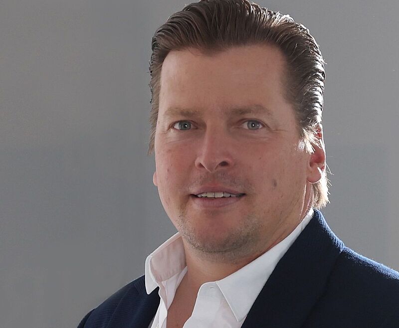 Pascal Zahl vertritt bereits seit 11 Jahren die kleinen und mittelständischen Reiseveranstalter im DRV und kandidiert nun erneut für den Vorstand. Ein Mann mittleren Alters mit kurzen, nach hinten frisierten Haaren trägt ein weißes Hemd und ein dunkelblaues Sakko mit einem Einstecktuch. Er blickt leicht lächelnd in die Kamera vor einem neutralen grauen Hintergrund.