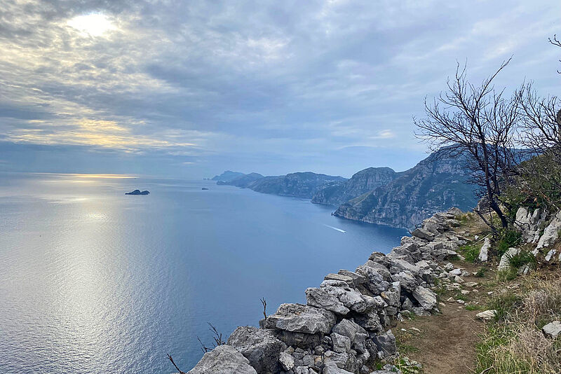 Blick vom „Pfad der Götter“ auf die Amalfi-Küste in Richtung Westen. Im Hintergrund ragen die Felsen der Insel Capri aus dem Meer