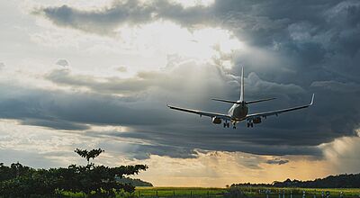 Der Europäische Gerichtshof hat entschieden, dass ein Blitzeinschlag in ein Flugzeug als außergewöhnlicher Umstand gilt Flugzeug bei der Landung unter dramatischem Wolkenhimmel mit Sonnenstrahlen.