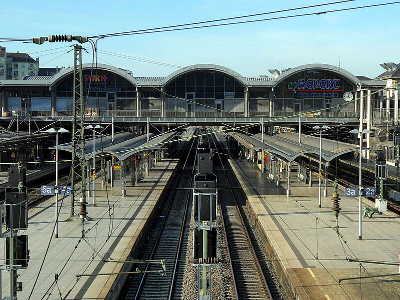 Der Mainzer Hauptbahnhof mit leeren Gleisen und Bahnsteigen von erhöhter Perspektive fotografiert. Im Vordergrund sind Oberleitungen und elektrische Kabel zu sehen.