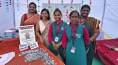 Einige Inderinnerin im Sari stehen an einem Messestand