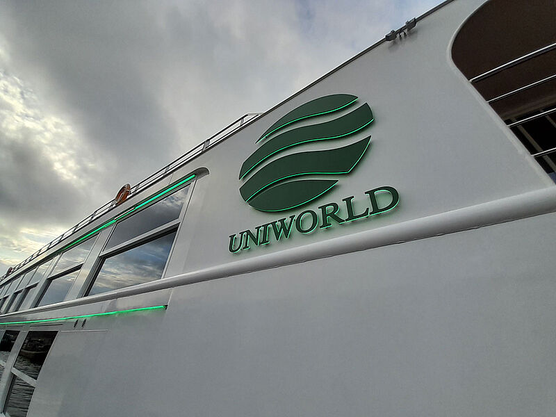Die US-amerikanische Flusskreuzfahrtmarke Uniworld vertreibt nicht mehr in Deutschland Großes Reederei-Logo an der Bordwand eines Flusskreuzfahrtschiffes