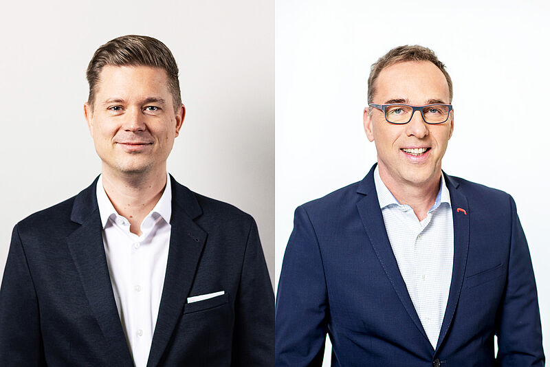 Zwei Männer in Business-Outfits nebeneinander in einem geteilten Bild. Der Mann auf der linken Seite hat kurze braune Haare, trägt einen dunklen Anzug mit einem weißen Hemd und hat einen dezenten Gesichtsausdruck. Der Mann auf der rechten Seite trägt eine Brille, hat kurze braune Haare mit grauen Strähnen, trägt einen dunkelblauen Anzug mit einem hellblauen Hemd und lächelt freundlich. Beide haben helle Haut und stehen vor neutralen Hintergründen