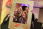 Vier Frauen blicken durch einen goldenen Rahmen auf dme 20 Jahre together steht