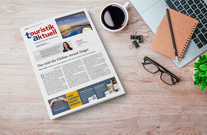 Ein Tablet mit der neuen Ausgabe von touristik aktuell auf einem Tisch daneben steht eine Tasse Kaffee