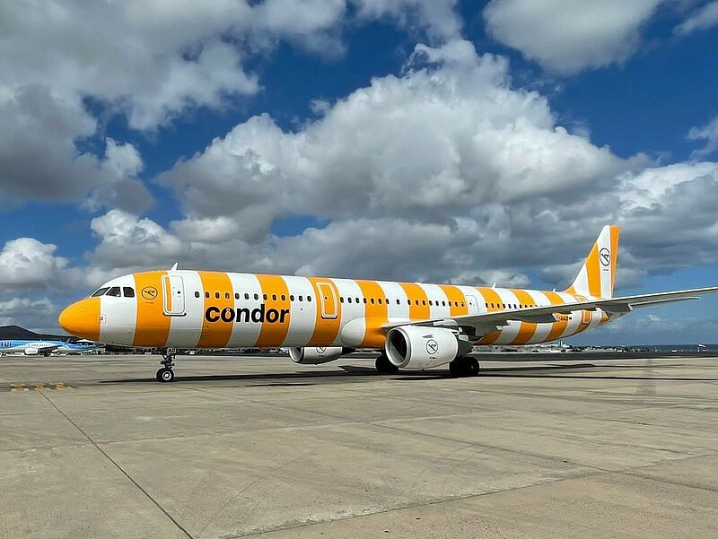 Condors Airbus-Maschinen müssen nicht am Boden bleiben- Foto: Condor Ein gelb-weiß-lackiertes Condor-Flugzeug steht am Boden.