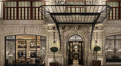 Das The One Monumental Palace in Porto wird künftig von H10 Hotels betrieben. Eingangsbereich des The One Monumental Palace in Porto mit beleuchteter Fassade im neoklassizistischen Stil und Glasvordach über dem Hoteleingang.