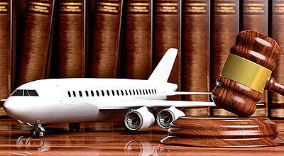 Auch Entschädigungsforderungen von Fluggästen sichert LTA künftig ab Ein Flugzeugmodell steht zusammen mit einem Richterhammer auf einem Holztisch, im Hintergrund sind Bücher zu sehen.