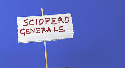 Ein Generalstreik sorgt am Freitag in Italien für erhebliche Beeinträchtigungen. Foto: Barbacane/iStock Handgemachtes Schild aus Wellpappe mit der roten Aufschrift „Sciopero Generale“ (italienisch für „Generalstreik“), befestigt an einem dünnen Holzstab, vor blauem Hintergrund.
