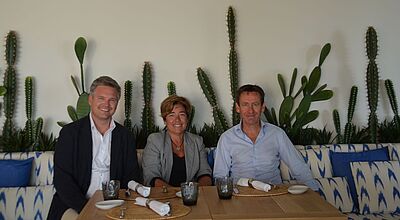 Zwei lachende Männer nehmen eine lächelnde Frau in die Mitte