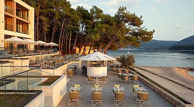 Eine Hotelterrasse mit Tischen und Stühlen direkt am Meer