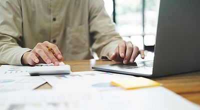 Person am Laptop mit Taschenrechner