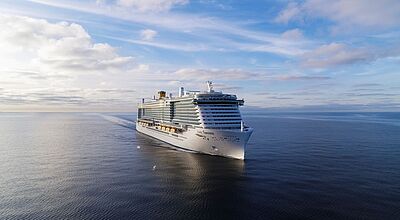 Kreuzfahrtschiff Costa Toscana fährt bei ruhiger See unter blauem Himmel über das offene Meer, aufgenommen aus der Luft von vorne links. Das moderne Schiff zeigt mehrere Decks mit Balkonkabinen und markantem gelbem Schornstein.
