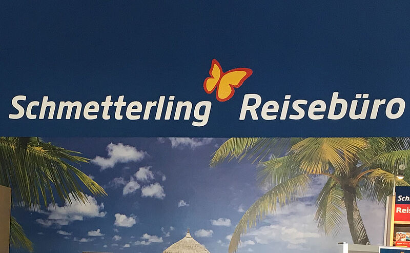 Schriftzug Schmetterling Reisebüro auf blauem Grund