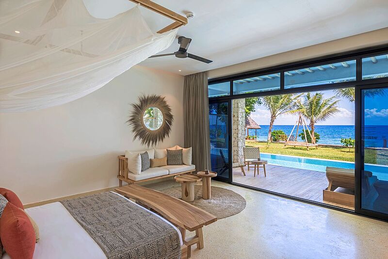 Blick in ein Hotelzimmer mit einem Swim-up-Pool, im Hintergrund sieht man Meer