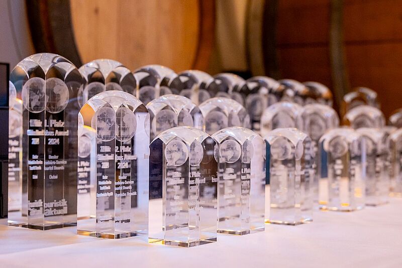 Zahlreiche transparente Trophäen der Globus Awards stehen aufgereiht auf einem Tisch, bereit für die Verleihung an die besten touristischen Partner und Reisebüros. 