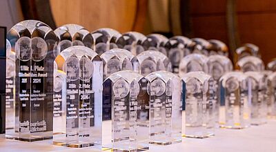 Zahlreiche transparente Trophäen der Globus Awards stehen aufgereiht auf einem Tisch, bereit für die Verleihung an die besten touristischen Partner und Reisebüros. 