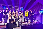 Viele Menschen auf der Bühne. Ein Mann hält ein schwarz-gelbes Borussia Dortmund Trikot in den Händen