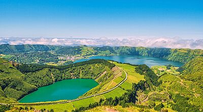 ein grüner Kratersee inmitten von grünen Bergen
