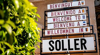 Schön gestaltetes Willkommensschild der Stadt Soller auf Mallorca in mehreren Sprachen.