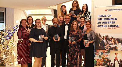 Michael Baden, CCO bei Nicko Cruises, und Cherryl-Ann Murray (Leiterin des Vertriebs-Außendiensts, li) mit den mitgereisten Nicko-Award-Preisträgern Gruppenfoto von Preisträgerinnen und Preisträgern bei der Nicko Cruises Award-Verleihung, alle halten glänzende Trophäen in den Händen