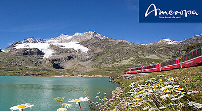 Zug auf Gleisen vor einem verschneiten Berggipfel