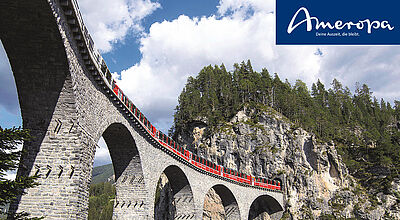 Panoramaaufnahme der berühmten Landwasser Viadukt-Brücke in der Schweiz, mit einem roten Zug der Rhätischen Bahn, der die beeindruckende Brücke überquert. Die Szene zeigt eine wunderschöne Berglandschaft mit grünen Wäldern und einem klaren blauen Himmel, perfekt für eine unvergessliche Zugreise durch die Schweizer Alpen