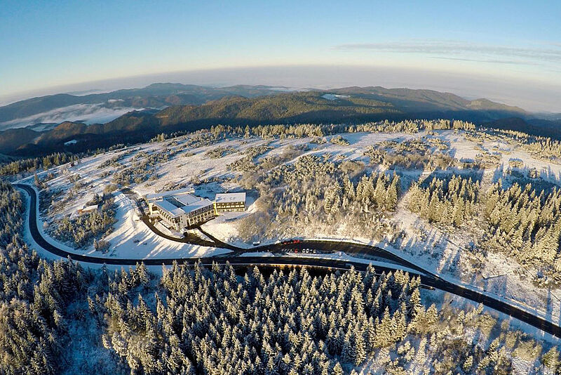 Ein Hotel auf einer Bergkuppe in einer verschneiten Winterlandschaft