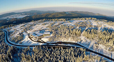 Ein Hotel auf einer Bergkuppe in einer verschneiten Winterlandschaft