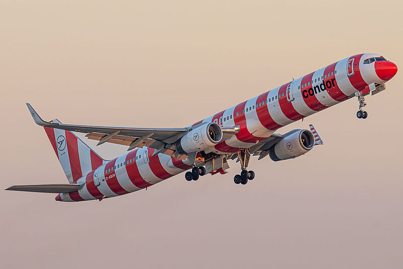 Ein Flugzeug von Condor des Typs Boeing 757-300 mit einer rot-weiß gestreiften Lackierung in der Luft