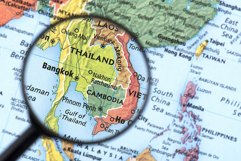Landkarte Südostasiens mit Lupe über Thailand, zeigt Nachbarländer wie Laos, Kambodscha und Vietnam.