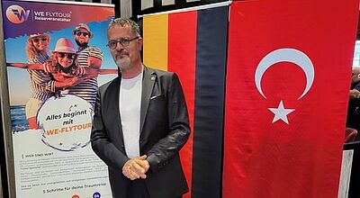Mann steht vor einer deutschen und einer türkischen Flagge