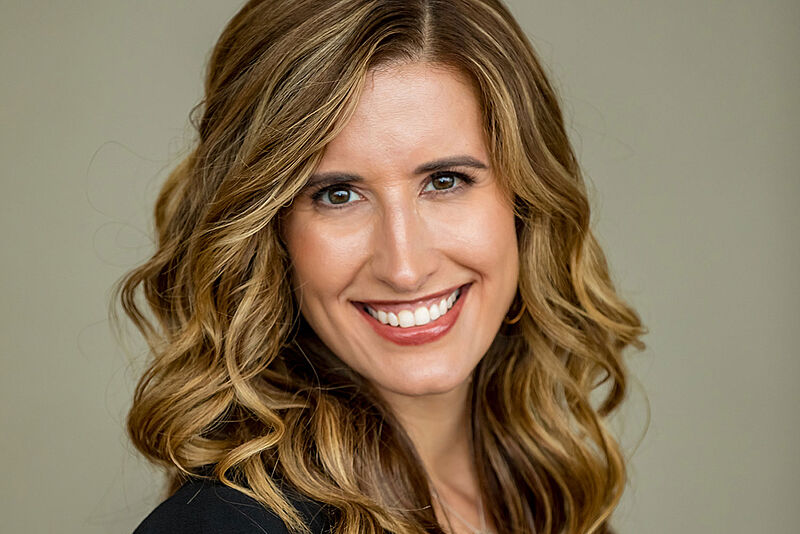 Porträtfoto von Leah Chandler, einer lachenden Frau mit langen, lockigen Haaren