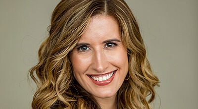 Porträtfoto von Leah Chandler, einer lachenden Frau mit langen, lockigen Haaren