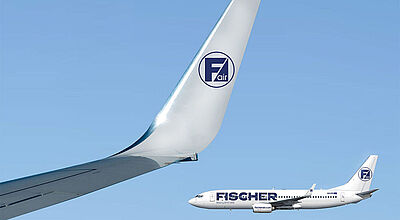 Bildmontage mit einem weißen Flugzeug von Fischer Air vor blauem Himmel und einem Winglet im Vordergrund, auf dem das Firmenlogo zu sehen ist.