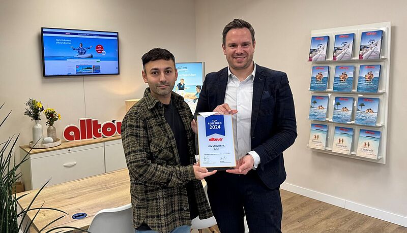 Florian Yavuz und Jan Flintrop mit einer Urkunde im Reisebüro