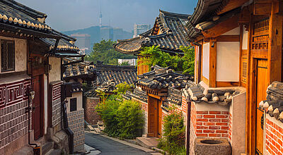 Verwinkelte Gasse mit traditionellen asiatischen Häusern vor einer Hügellandschaft in der koreanischen Hauptstadt Seoul