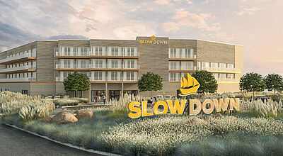 Ein neuerbautes Hotel mit Solar-Panel auf dem Dach, daneben ist ein Swimmingpool