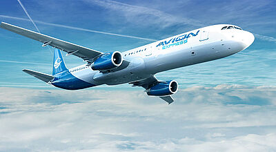 Ein blau-weißes Flugzeug der Airline Avion Express fliegt über Wolken, im Hintergrund ist blauer Himmel mit Kondensstreifen zu sehen