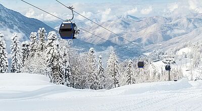 Österreich bietet Wintersportlern ab Dezember in vielen Regionen größere und modernere Bergbahnen. Foto: GKV/iStock Bild von einer Berglandschaft mit Schnee unter blauem Himmel und einem modernen Skilift.