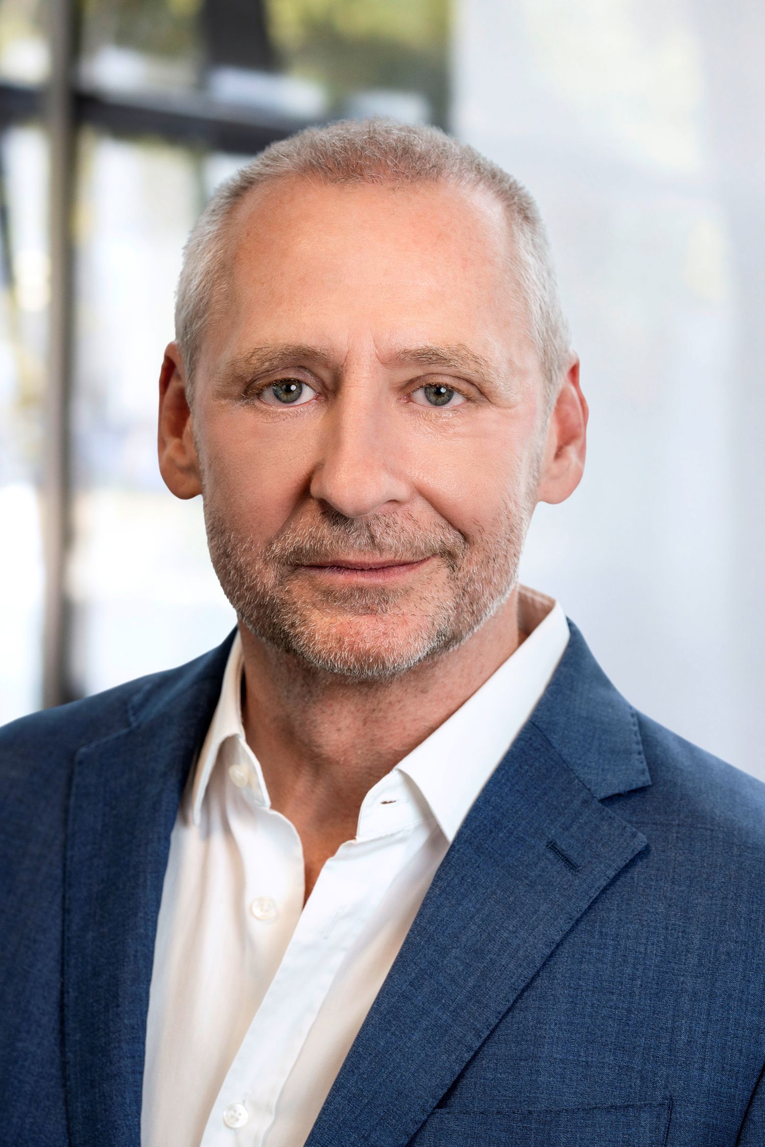 Porträt eines Mannes im blauen Anzug und weißem Hemd vor verschwommenem, hellem Hintergrund. Es ist der Geschäftsführer von Dertour Deutschland, Boris Raoul.