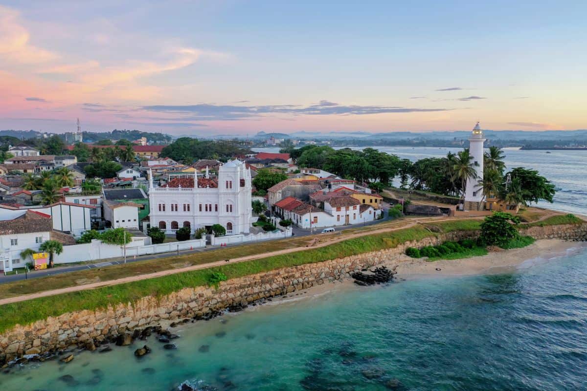 Luftaufnahme der Küstenstadt Galle in Sri Lanka bei Sonnenuntergang mit dem markanten weißen Leuchtturm, historischen Gebäuden und der steinernen Festung.