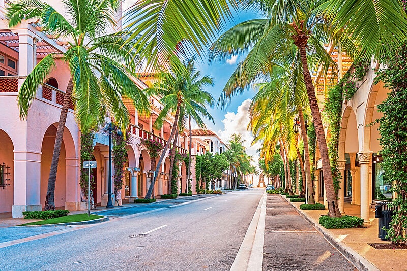 Die Worth Avenue in Palm Beach in Florida, eine Straße gesäumt mit Palmen und edlen Boutiquen.