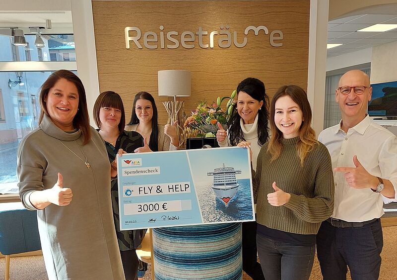 Uta Illing (Aida) und Reisebüro-Chef Patrick Leistner rahmen den Spendenscheck über 3.000 Euro ein
