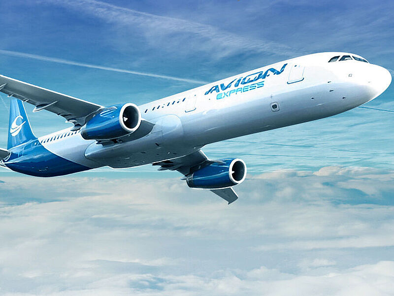 Ein blau-weißes Flugzeug der Airline Avion Express fliegt über Wolken, im Hintergrund ist blauer Himmel mit Kondensstreifen zu sehen