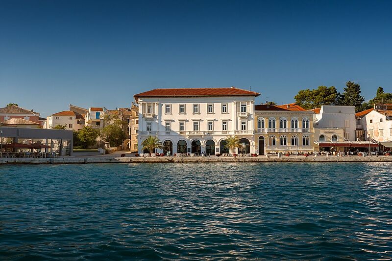 Historisches Küstengebäude mit mediterraner Architektur an der Promenade von Porec Zadar, Kroatien, bei sonnigem Wetter.